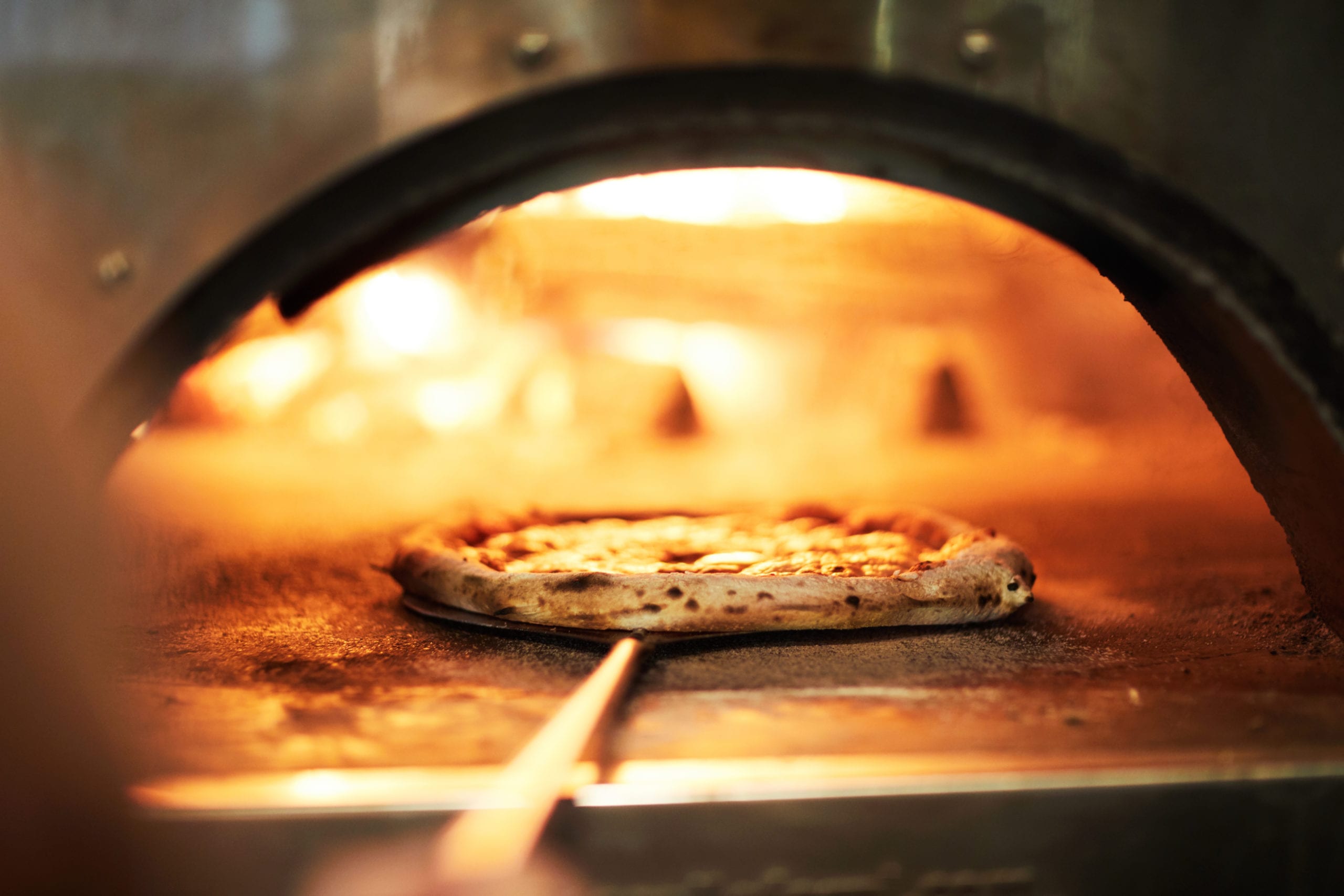 Pizza cooking in woodfired oven