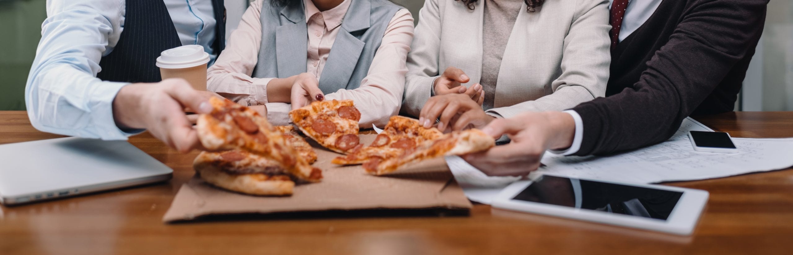 smiling multiethnic businesspeople eating pizza in office