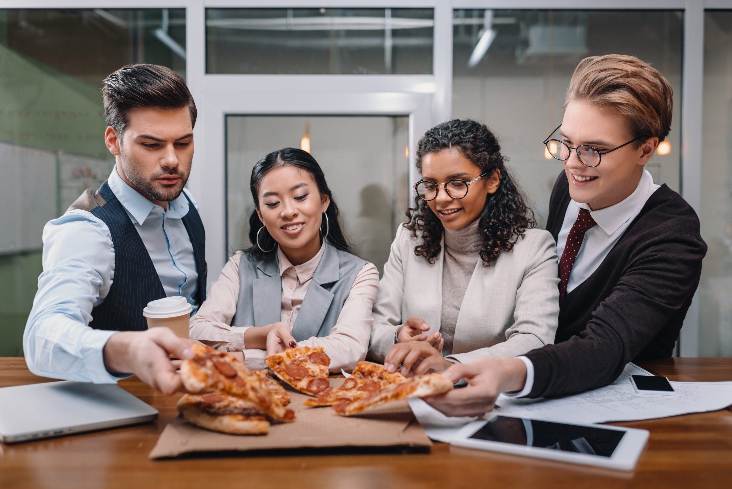 four executives eating a wood fired pizza from the wandering pizza co in their office